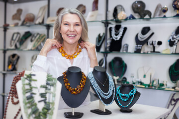 Adult woman chooses jewelry from turquoise and amber jewelery in the store