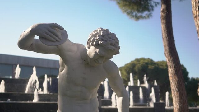 A close-up footage of white statue in the background of decorative fountain with flowing water. 