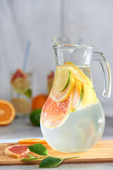 Health care, fitness, healthy nutrition diet concept. Fresh cool homemade citrus infused detox water with grapefruit, orange, lemon and lime and ice in a jug and glasses for spring summer days.