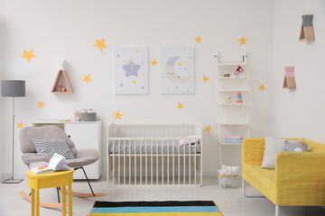 Stylish baby room interior with crib, rocking chair and sofa