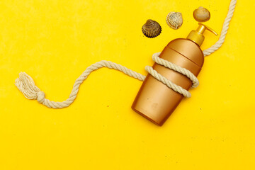 Flat lay composition with , sunscreen pray and seashell and knot rope on yellow background. Summer vacation backdrop