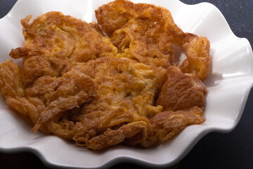 Omelette in a white plate on a black background