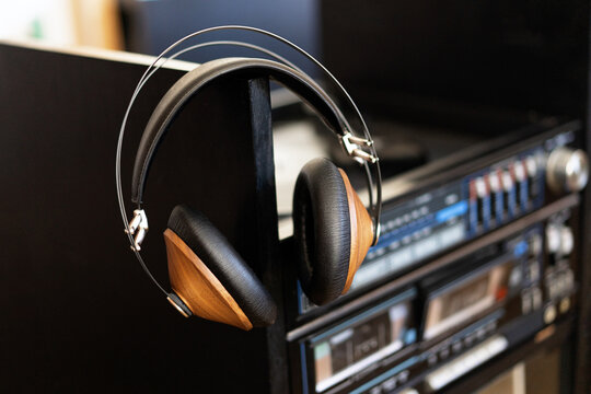 Vintage headphones made of wood are on a black vinyl in a record player