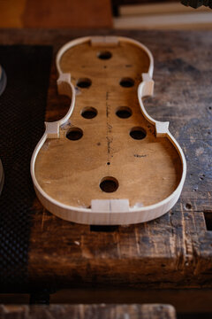 High angle of wooden soundboard with round holes and attached shells on workbench in workshop