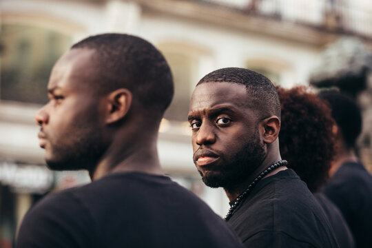 Black people on street with serious expression. The man is looking at camera