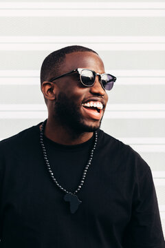 Happy black man posing and smiling over white background and wearing black sunglasses