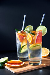 Health care, fitness, healthy nutrition diet concept. Fresh cool homemade citrus infused detox water with grapefruit, orange, lemon and lime and ice in glasses on dark background.
