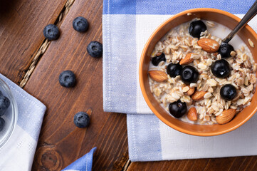 breakfasr with oatmeal porridge with blueberries, fruits,  almonds and coconut milk. Healthy and tasty vegan breakfast. top view, flat lay. close up