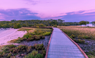A raised walkway follows the shoreline of the bay at Paradise Point, Queensland at sunrise