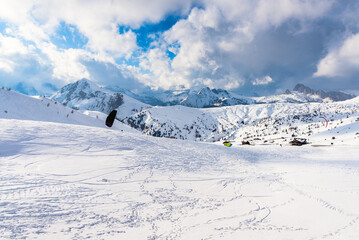 People kite skiing in a magnificent snowy mountain scenery in the European Alps on a sunny winter day