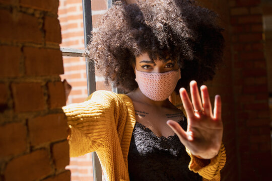 Portrait of a young African American woman with a crocheted facemask on.