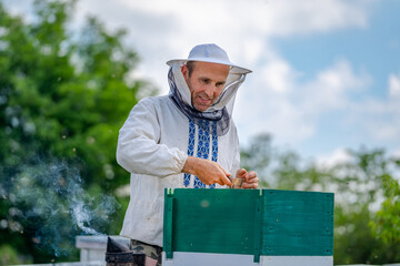 Beekeeper at apiary at the summer day. Man working in apiary. Apiculture. Beekeeping concept.