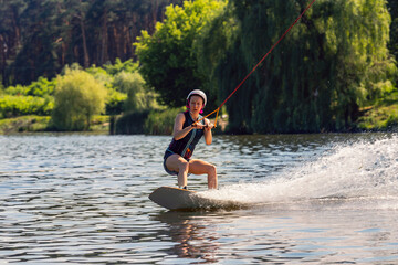 Woman riding wakeboard. Сuts waves and raises splash in a summer lake
