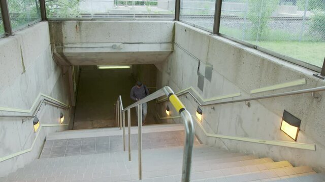 High quality 4k video of a young man who climbs the stairs at the station and holds a phone in his hands and a backpack on his back. A man hurries on a train, bus, airplane subway, transport 