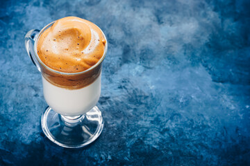 Dalgona coffee. Trendy Korean drink creamy whipped coffee with milk on a blue rustic background.