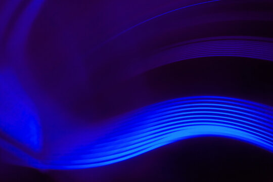 Close-up abstract image of vibrant blue light trails against black background