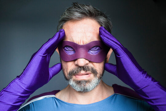 Close-up of superhero with headache against gray background