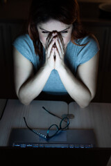Tired, exhausted woman in frustration working overtime on a laptop. A female freelancer in...