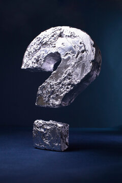Close-up of silver question mark against black background