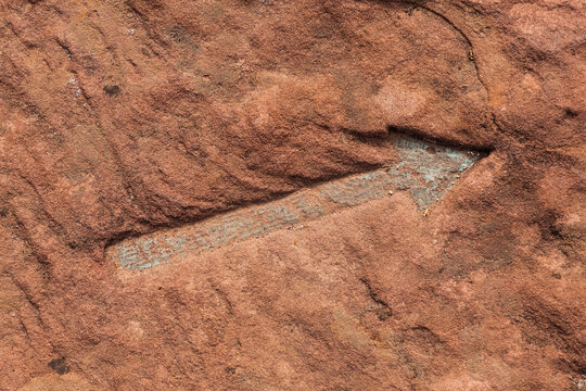Full frame shot of arrow symbol on brown rock