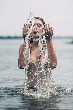 Woman with eyes closed splashing water in lake