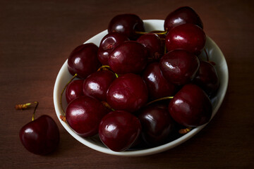 Fresh red cherries in a white cup on a wooden table