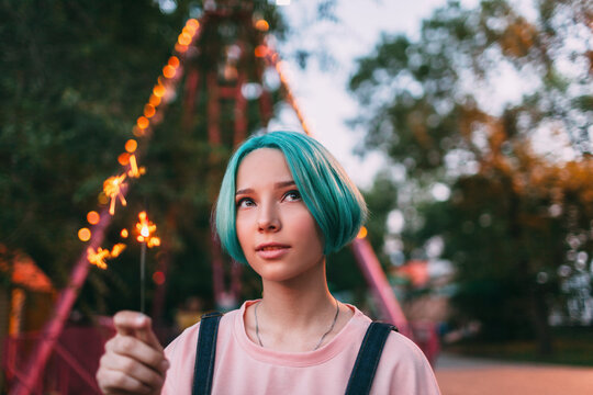Portrait of teenage girl holding illuminated sparkler outdoors