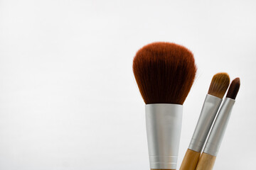 Three make-up brushes isolated on white background. Space for text on the left