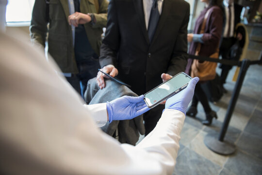 Airport security agent checking boarding pass on passenger smart phone