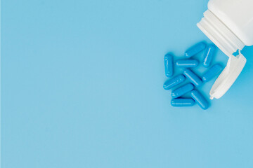 Blue capsules, pills on a blue background. Capsules in a white jar. Vitamins, nutritional supplements for women's health