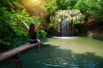 Girl and a beautiful waterfall with a lagoon for relaxation in the summer.