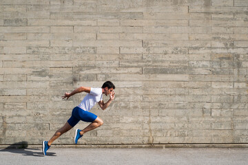 Caucasian athlete making a start in front of an irregular grey wall background