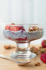 Chia pudding with raspberry chia jam in a glass garnished with strawberries, raspberries and granola. Healthy breakfast concept