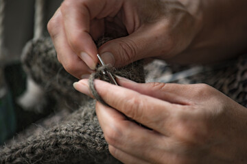 Woman knits sweater using knitting needles. Needlework