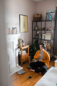 Young Woman Listening To Guided Meditation At Home