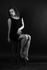 Black and white portrait of a cute curly girl in a black dress
