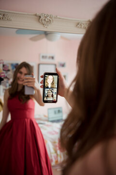 Teenage girl in prom dress video chatting with friends on smart phone