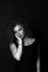 Fototapeta premium Black and white portrait of a cute curly girl in a black dress