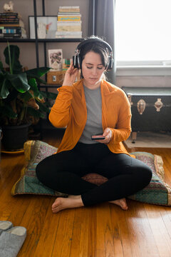 Young woman listening to guided meditation on phone