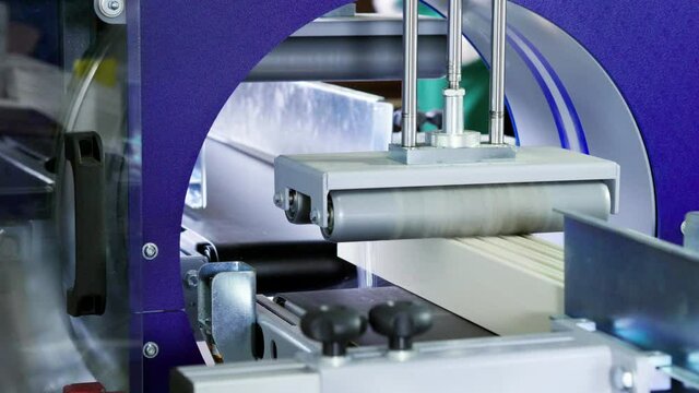 Manufacturing furniture factory with computerized automatic machinery. A modern automated machine packaging furniture parts, wrapping it in a thin clear plastic material. 4K