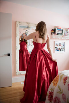 Teenage girl in red prom dress video chatting with friends