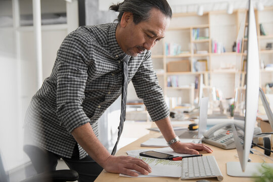Senior Asian man reading document on desk