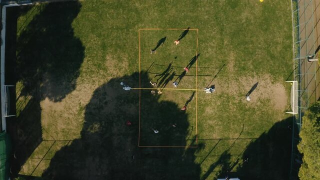 Aerial View of a Sport Field between green trees. People playing basketball. Drone footage 4K