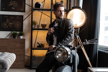 Naklejka na ściany i meble Stylish young man in leather jacket sitting on motorbike.