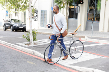 African American man crossing the street and holding his bike