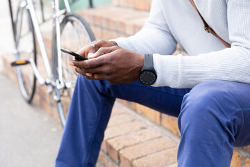 African American man sitting on stairs and using his phone