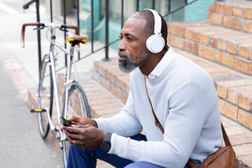 African American man sitting on stairs and listening music