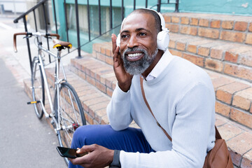African American man sitting on stairs and using his phone
