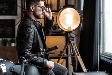 Stylish young man in leather jacket sitting on motorbike.