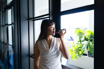 Asian woman having a phone call and looking outside